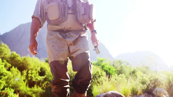 Fly fisherman walking in river with fishing rod