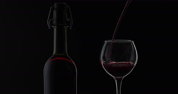 Rose Wine. Red Wine Pour in Wine Glass Over Black Background. Silhouette
