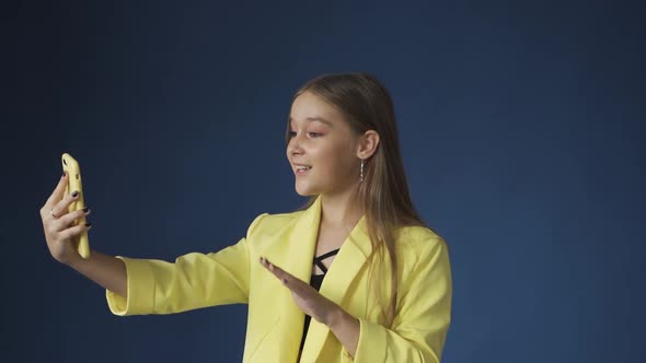 Young Girl Chatting with Friends with Smartphone Camera on Blue Background