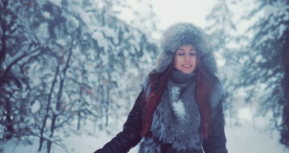 Beautiful and Happy Woman Walks in the Winter Forest