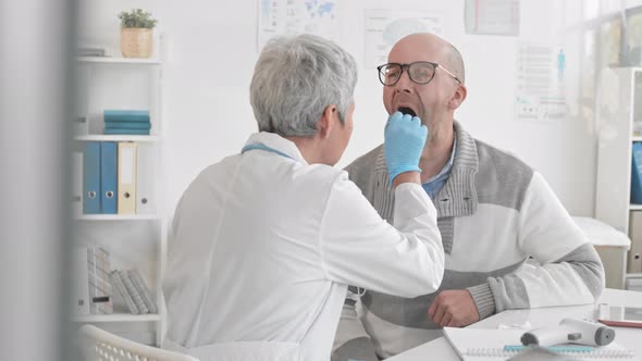 Doctor Using Tongue Depressor on Patient