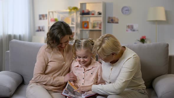 Happy Female Family Members Watching Photo Album Pictures, Having Fun Together