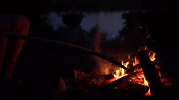 The Man Straightens the Coals in the Fire. The Fire Is Burning in the Middle of the Night Close-up.