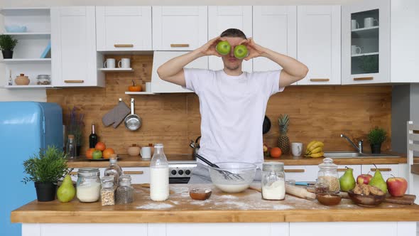 Young Funny Man Making Apple Eyes Dancing In Kitchen