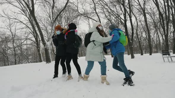 Schoolchildren Wearing Masks Throw Snowballs in the Park in Winter