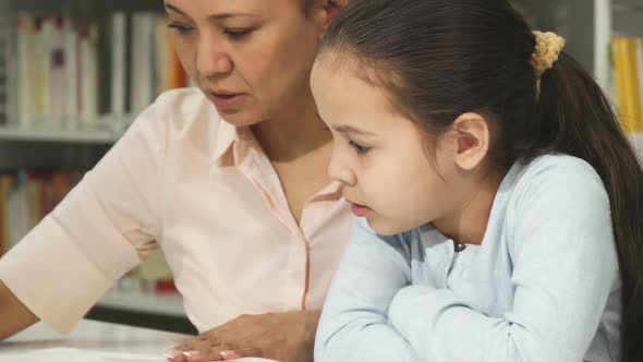 Cropped Shot of a Cute Little Girl Reading a Book with Her Mother