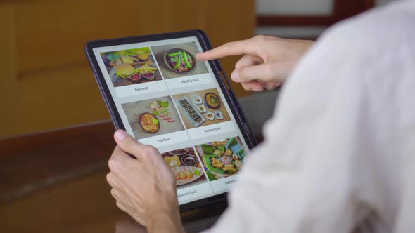 A Man Orders Food for Lunch Online Using Tablet. Online Shoping Concept