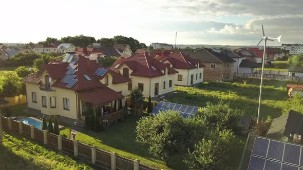 Aerial view of an autonomous house with solar panels on roof and wind generator turbine 