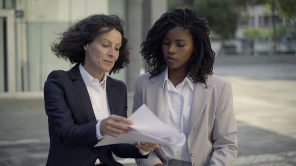 Front View of Confident Colleagues Discussing Documents on Street