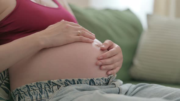 Close Up of Pregnant Woman Holding Her Big Belly While Sitting on Sofa