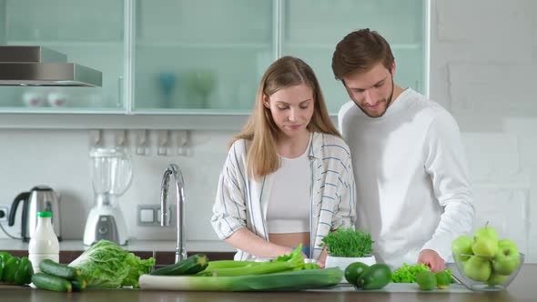 Healthy Food Young Couple Prepares a Salad in the Kitchen Man and Woman Cuts Herbs and Green