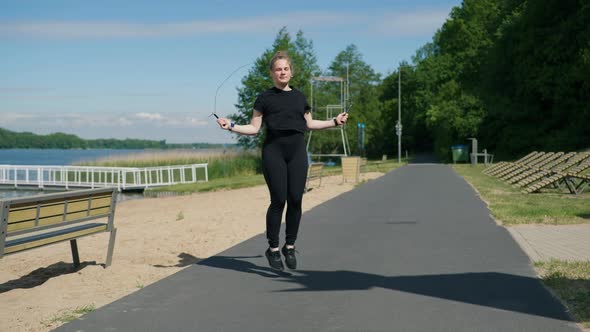 Young Girl Jumping Rope on the Embankment on a Sunny Day