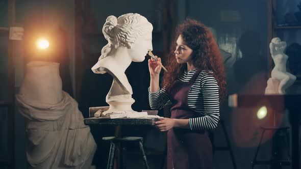 Lady Artist is Looking at the Gypsum Sculpture After Brushing It