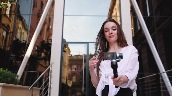 Video Blogging. Woman With Camera Near Modern Business Building