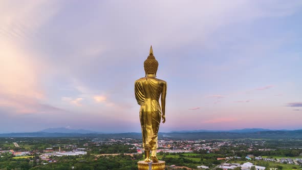 Golden standing Buddha statue overlook city on mountain at Wat Phrathat Khao Noi temple – time lapse