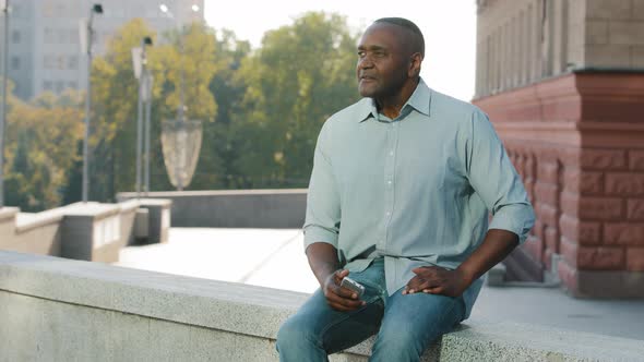 Stressed Frustrated African American Man of Retirement Age in Casual Clothes Shirt and Jeans Sitting