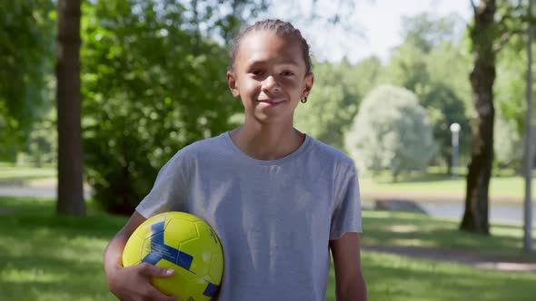 Teenage African Boy Smiling Happy Holding Ball Standing at Park