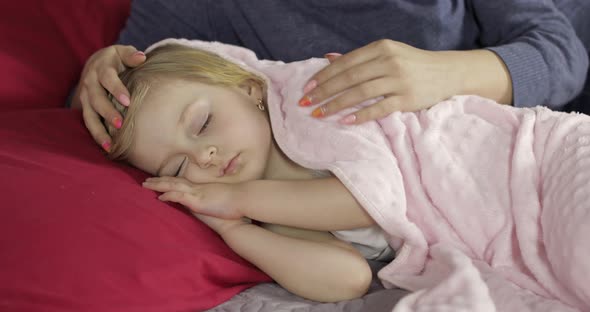 Young Mother Taking Care of Her Little Baby Girl While She Sleep. Girl on Bed