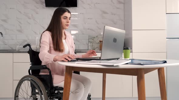 Young Disabled Woman in Wheelchair Working with Laptop and Tablet at Home