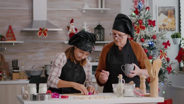 Grandma Explaining to Grandchild How to Make Traditional Xmas Homemade Gingerbread Dessert