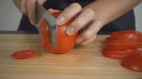 woman making salad healthy food and chopping tomato on cutting board in the kitchen.