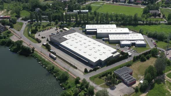 Moving Aerial Side Shot of Industrial Warehouse Loading Dock where Many Truck with Semi Trailers Loa