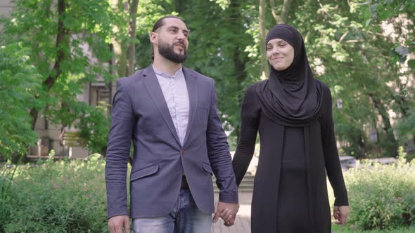 Portrait of Happy Loving Middle Eastern Couple Strolling in Sunny Summer Park. Middle Shot of