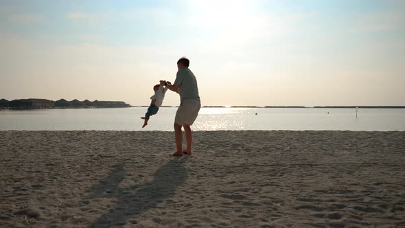 The Water Father Circles the Child By the Handles By the Ocean Coast Wide Shot