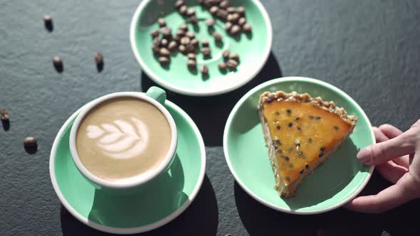 Female Caucasian Hand Taking Plate with Sweet Pie From Table with Coffee and Beans