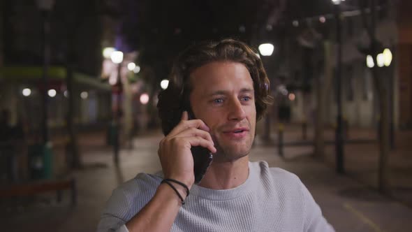 Caucasian male talking on the phone and holding a cup in the evening