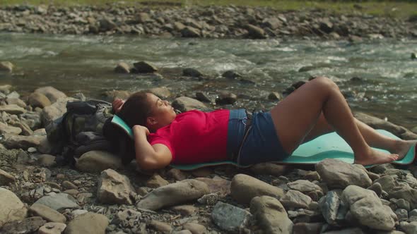 Peaceful Pretty African American Woman Backpacker Relaxing on Mountain Riverbank on Trek