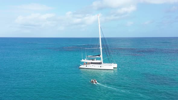 Tourists ferried to catamaran with inflatable boat, azure blue Caribbean