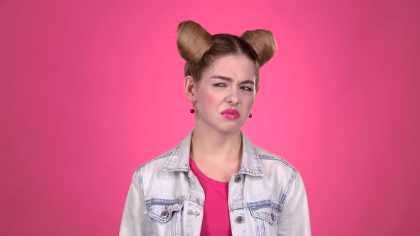 Teen Shows a Thumbs Down, She's Upset. Pink Background. Slow Motion