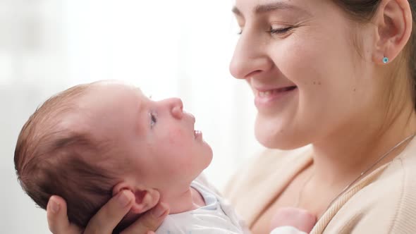 Closeup Portrait of Smiling Mother with Adorable Newborn Baby Against Big Bright Window