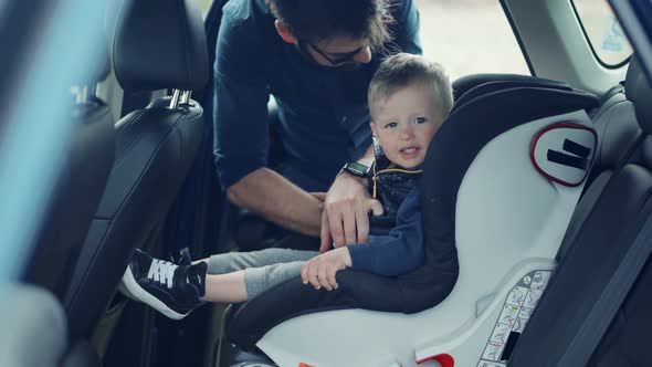 Happy Family Father And Child Boys Leisure. Father Fasten Son In Car Seat. Carefree Dad Baby Seat.