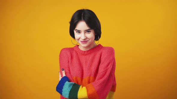 Cute Woman Wearing Red Sweater with Rainbow Sleeves Showing Bellissimo Gesture and Smiling to Camera