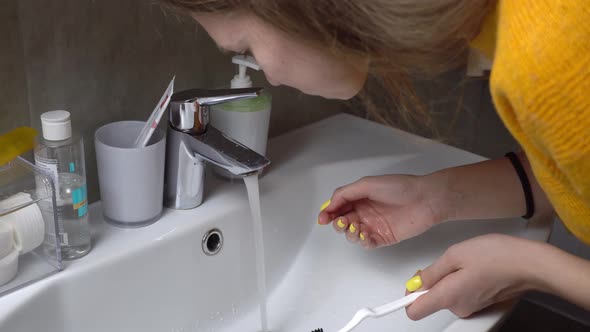 The image of a pretty woman, brushing her teeth, rinsing her mouth with water.