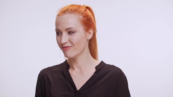 Middleaged Caucasian Woman with Colored Orange Hair and Dark Brown Shirt Smiling Flirting Winking