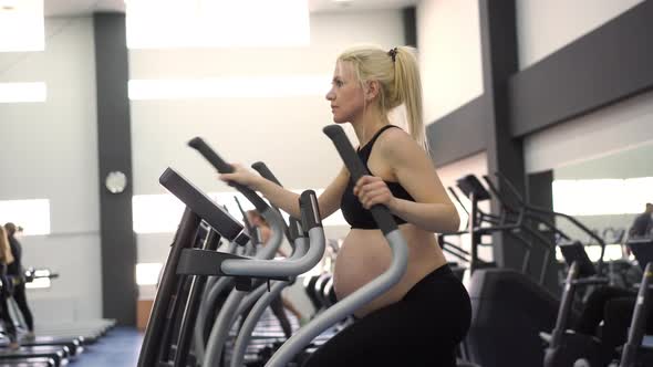 Pregnant Woman Training Elliptical Trainer in Gym Cardio Exercises on Running Simulator