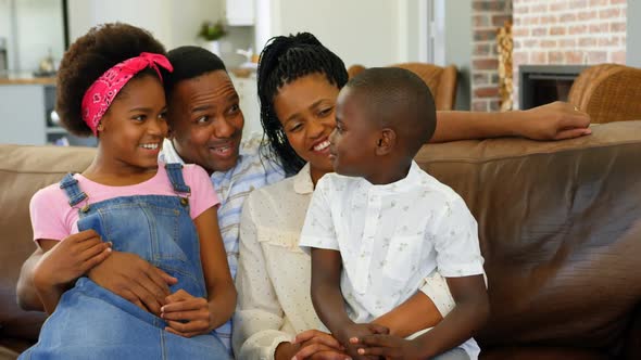 Front view of young black family sitting on the couch in a comfortable home 4k