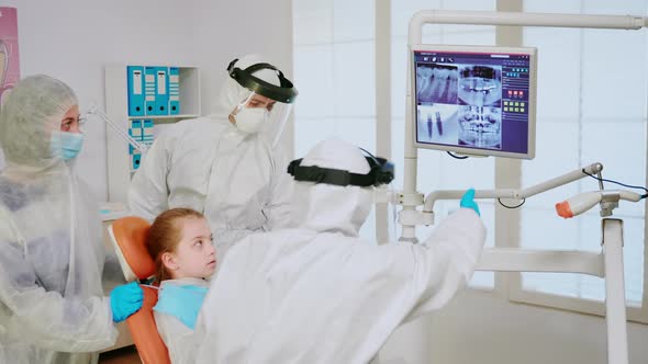 Stomatologist in Coverall Explaining Dental Problem Using Digital Monitor