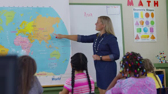 Teacher gives lesson in school classroom and students raise hands