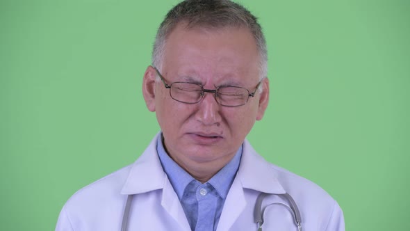 Face of Stressed Mature Japanese Man Doctor Looking Sad and Crying