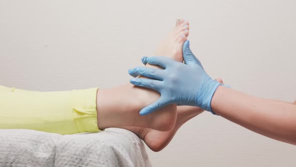 Podologist in blue medical gloves massages a female flat foot. Closeup. Slow motion