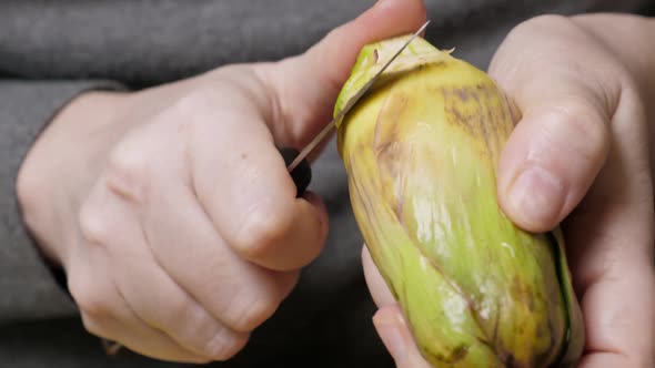 Woman Cleaning Artichokes with Knife