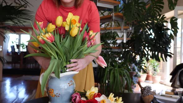 Smiling woman with bunch of tulips in a vase at home