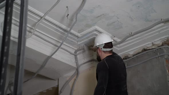 Fat Bearded Adult Man in Protective Helmet and Black Tight Fitting Clothing Remove Construction