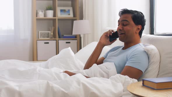 Happy Indian Man Calling on Smartphone in Bed