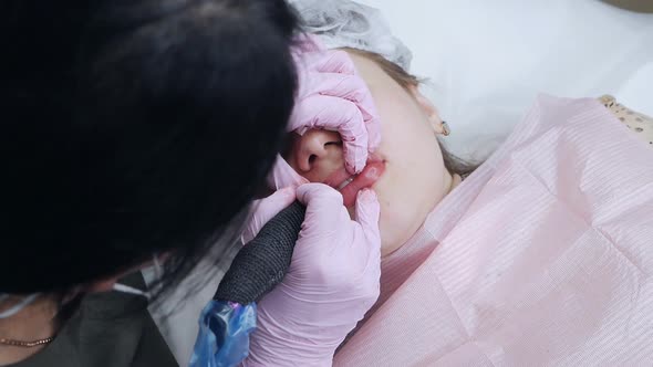 Young Woman Having Permanent Makeup on Lips in Beautician Salon