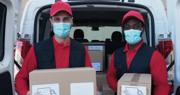 Multiracial delivery men holding packages while wearing safety face masks